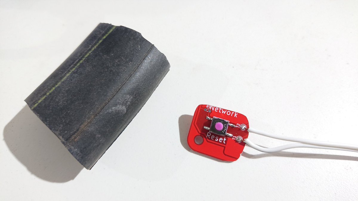 The small button circuit board with the button soldered on, as well as two wires which run out of view. Next to that is a short section of old bike inner tube