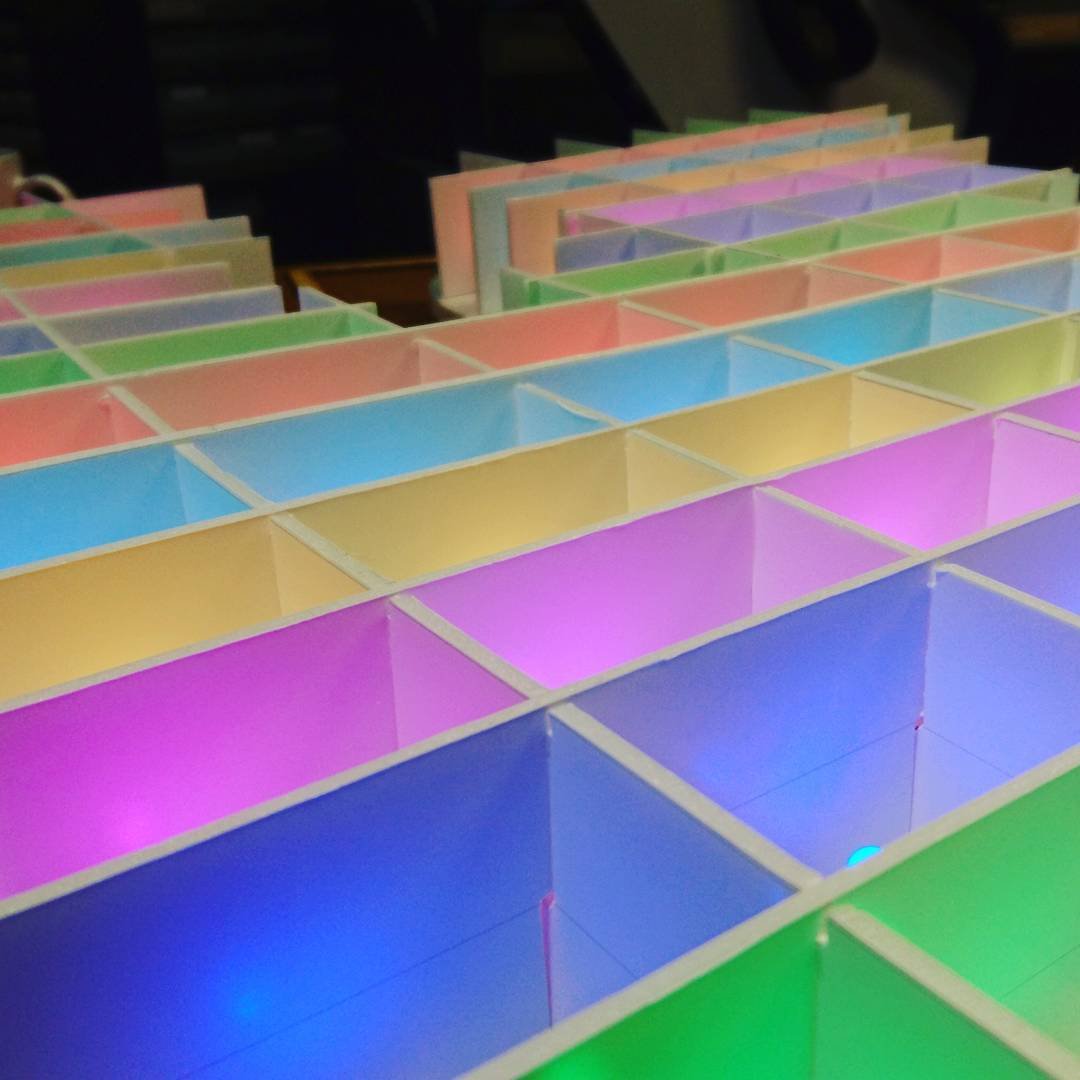 Grid of boxes formed by long strips of foamcore cut so that the horizontal and vertical strips lock together, illuminated by an LED in each square