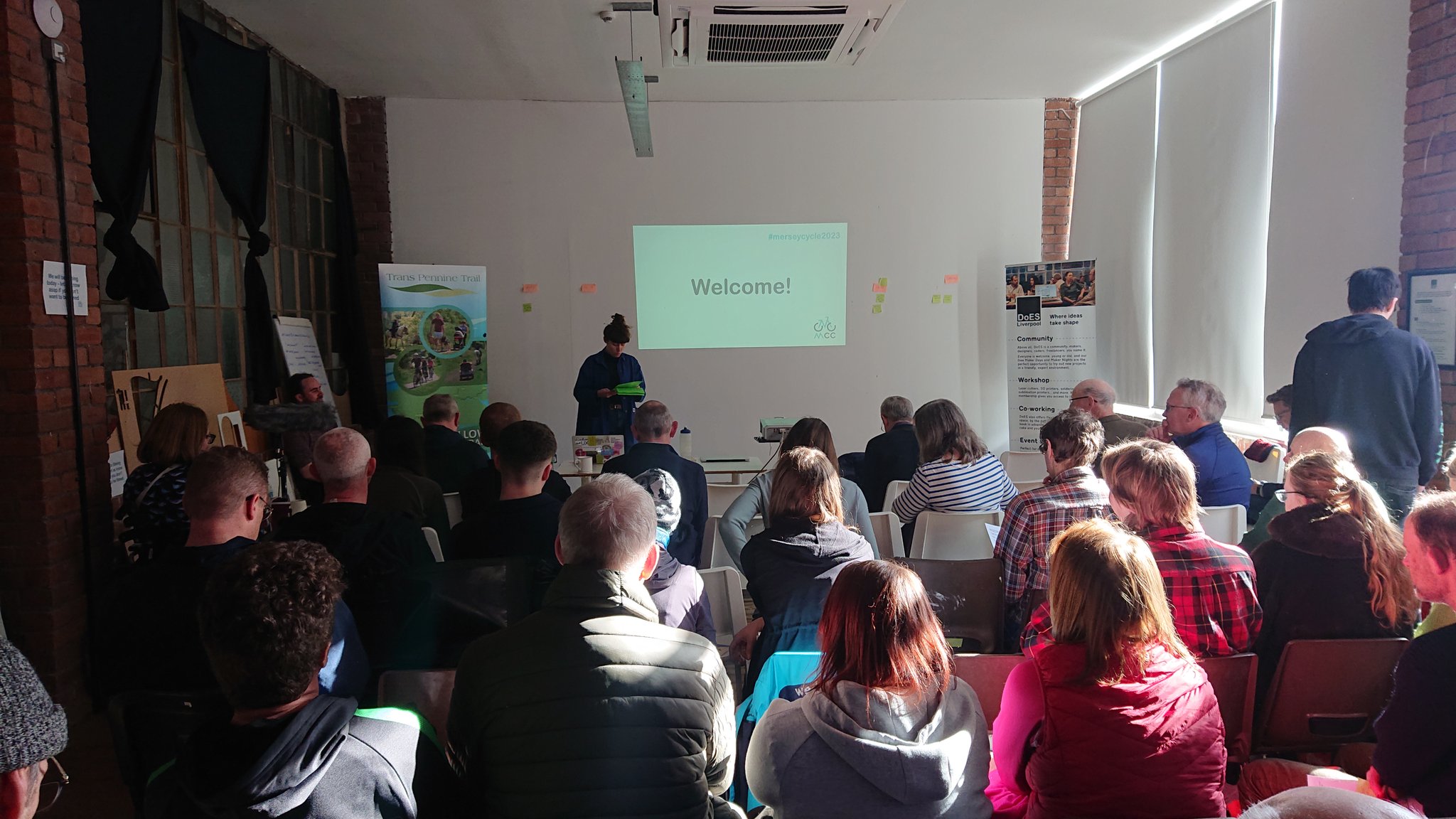 Rows of people sat watching Kirsty presenting the welcome session at the Merseyside Cycling Campaign AGM