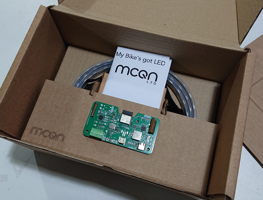 The completed box insert for the My Bke's got LED packaging ready to ship. A brown corrugated cardboard box, with an insert holding a green pcb, addressable led strip, battery and instructions