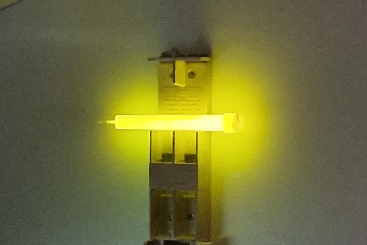 A picture of a glowstick fixed to the wall of a train as emergency lighting