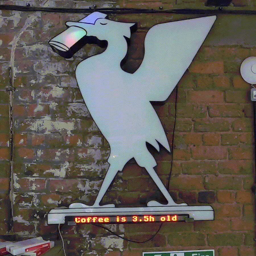 A Liver Bird sign mounted on a brick wall.  It lights up with agrid of different-coloured squares, and after it's fully illuminated with a rainbow of colour, it then fades out again.