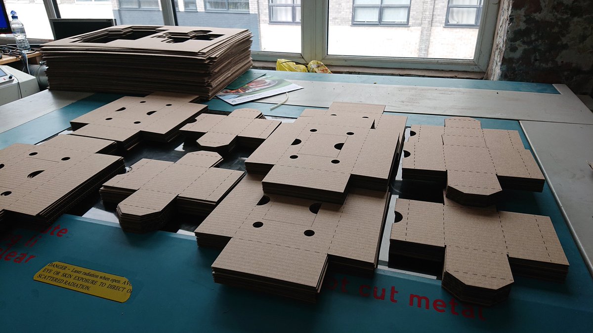 An array of piles of carefully laser-cut cardboard laid out on the top of a laser-cutter