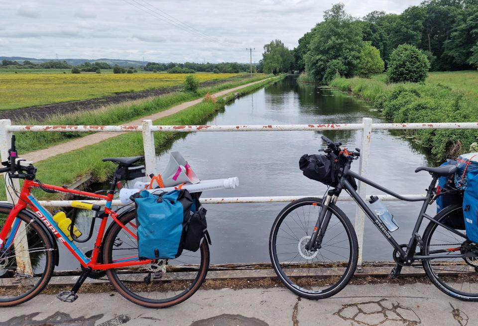 Two bikes, loaded with luggage, propped up against the railings of a bridge over a canal. Unfortunately not the Union canal in Scotland