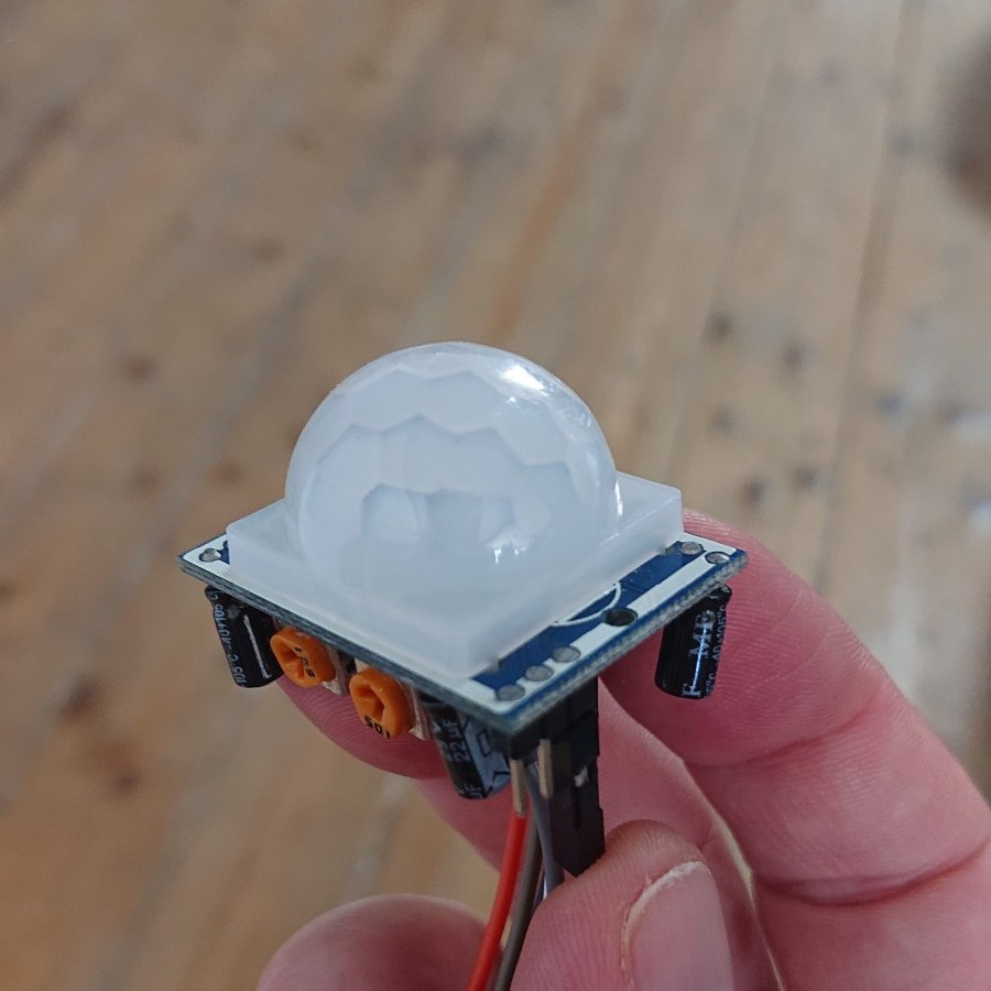 PIR sensor: a small circuit board topped with a hemispherical dome lens, with two adjustment pots below and a few components visible from the underside